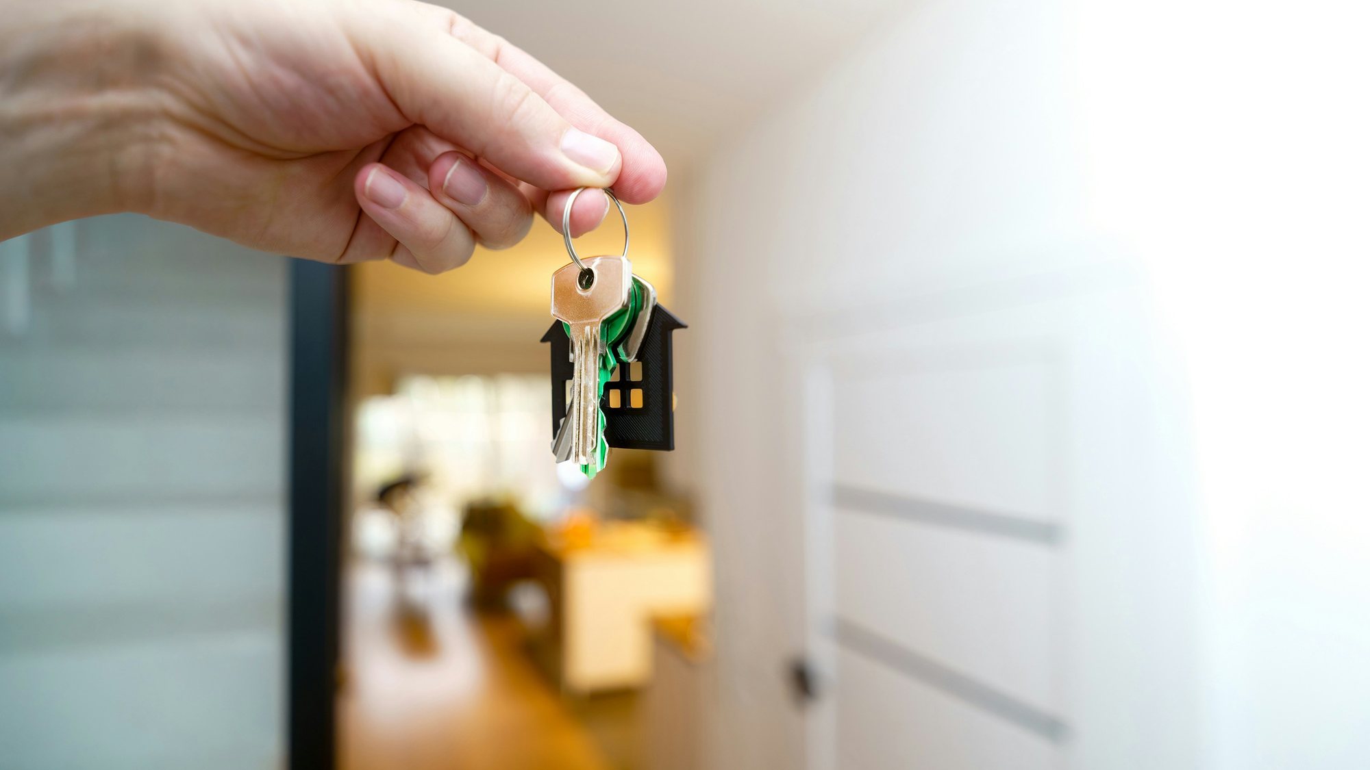 A hand holding house keys by an open door