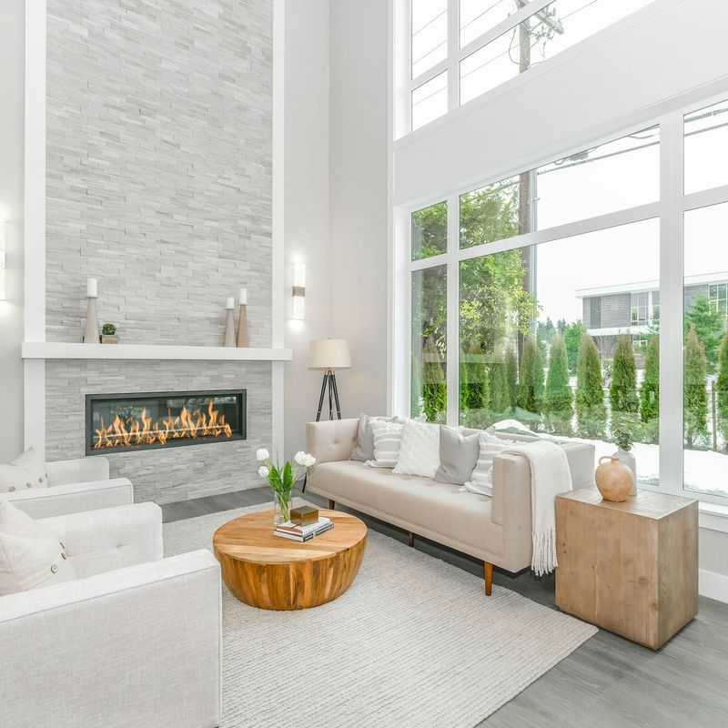 A tall living room with a fireplace and large windows